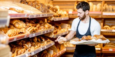 Pekař doplňuje v supermarketu pečivo