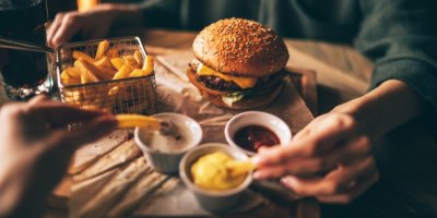 Dva lidé jí burger a hranolky