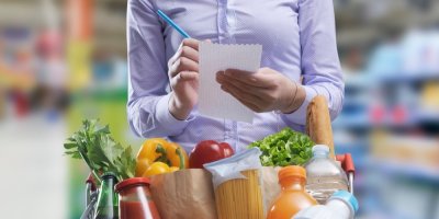 Žena s plným nákupním vozíkem v supermarketu