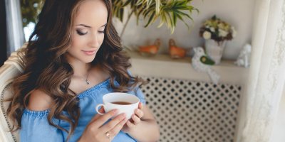 Těhotná žena drží hrnek s kávou