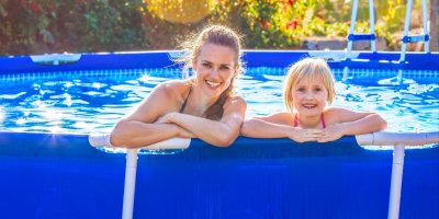 Žena a dívka se opírají o okraj bazénu s kovovou konstrukcí