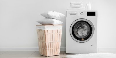Pračka, koš na prádlo a na něm polštáře