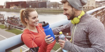 Dva běžci na mostě drží lahve v ruce