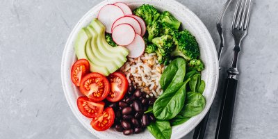 Zdravé jídlo z rýže, rajčat, fazolí, ředkviček, avokáda, brokolice a polníčku