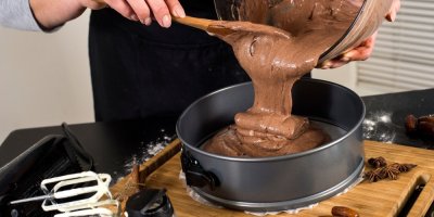Člověk nalévá čokoládový krém do formy na koláč