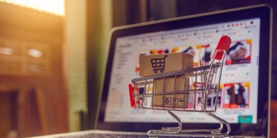 On-line nakupování na notebooku. Před počítačem je nákupní vozík