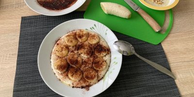 Špaldová kaše, servírovaná na bílém talíři, zdobená banány a grankem