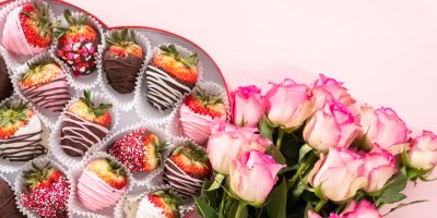 Dárková krabice, ve které jsou různě ozdobené jahody v čokoládě, s kyticí růží