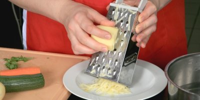 Žena, která strouhá syrovou bramboru na struhadle