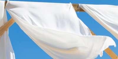 Záclony, pověšené venku na dřevěné konstrukci