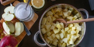 Nakrájená jablka v hrnci, jablka a cukr na prkénku