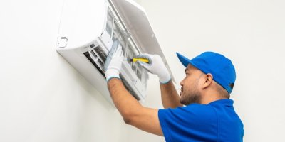 Muž instaluje nástěnnou klimatizaci