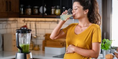 Těhotná žena pije ze sklenice