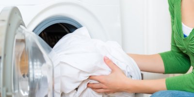 Žena dává bílé prádlo do pračky