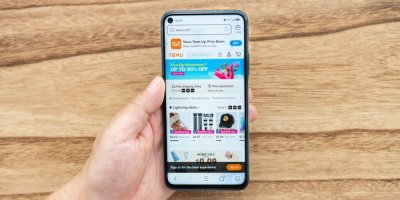 Ruka, která drží v ruce mobil s otevřenou aplikací Temu
