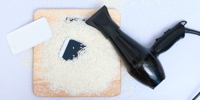 Mobilní telefon zasypaný rýží, vedle něj fén