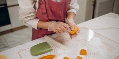 Člověk v kuchyni připravuje barevné těsto na mochi