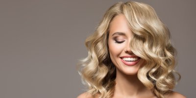 Žena s blonďatými vlnitými vlasy se usmívá