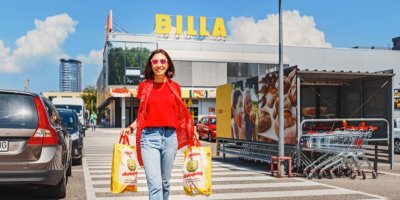 Žena před obchodem Billa s nákupními taškami