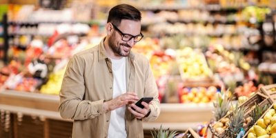 Muž v supermarketu drží mobil
