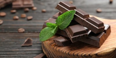 Kousky čokolády, položené na dřevěném prkénku, ozdobené lístky máty