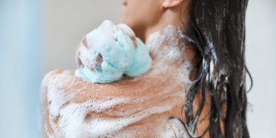 Žena aplikuje mýdlo na pokožku pomocí žínky