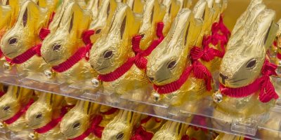 Čokoládoví zajíčci Lindt ve zlatém obalu s červenou mašlí v regálu v obchodě