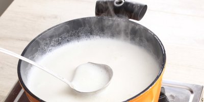 Mléko se vaří v hrnci, ve kterém je naběračka