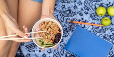 Žena jí hůlkami tofu se zeleninou