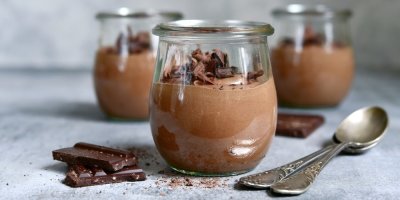 Tři skleničky s čokoládovou pěnou, vedle lžičky a čokoláda