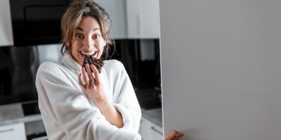 Žena provinile jí čokoládu u ledničky