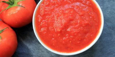 Malá miska s rajským protlakem, vedle rajčata