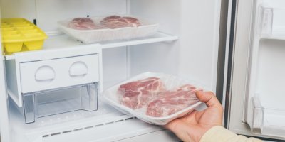 Ruka vkládá maso do lednice