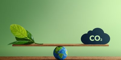 Miniaturní zeměkoule podpírá váhu, na jedné straně list, na druhé mrak se znakem CO2