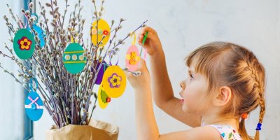 Holčička věší dekorace ve tvaru vajíček na kočičky