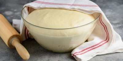 Kynuté těsto v míse, překryté utěrkou