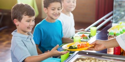 Tři kluci čekají na oběd ve školní jídelně