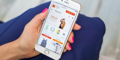 Žena drží v ruce telefon s aplikací AliExpress