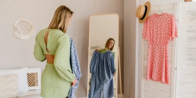 Žena si před zrcadlem zkouší šaty