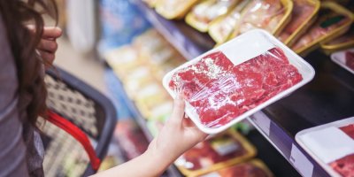 Žena si v obchodě prohlíží zabalené maso