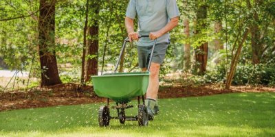 Muž s rozmetačem travního hnojiva