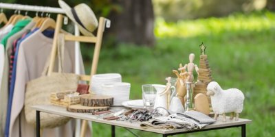 Na stole leží různé předměty od brýlí až po dekorace, vedle visí oblečení