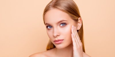 Mladá žena si prohlíží svou pleť a dotýká se jí