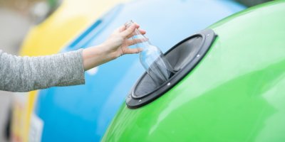 Záběr na vyhazování čiré skleněné flašky do kontejneru