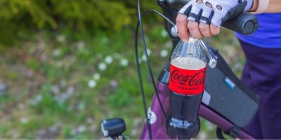 Cyklista drží láhev nápoje Cola Zero