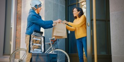 Žena přebírá objednané jídlo od doručovatele