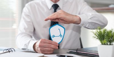 Muž drží v ruce papír s obrázkem koloběžky