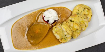 Svíčková s karlovarským knedlíkem, servírovaná na bílém talíři