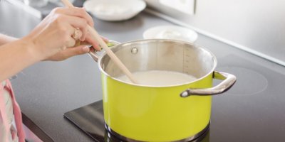 Žena převařuje mléko na plotně