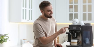 Muž si připravuji kávu na automatickém kávovaru